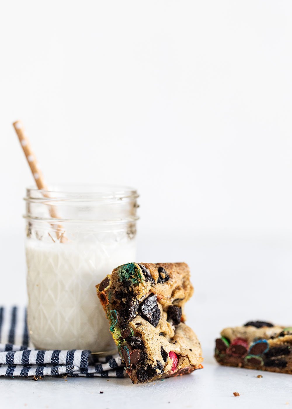 Loaded cookie bar leaning against glass of milk with a straw