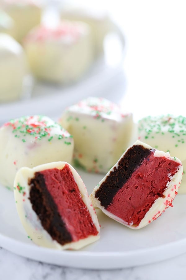Red Velvet Cheesecake Bites feature squares of homemade red velvet cheesecake dipped in white chocolate and garnished with festive holiday sprinkles! Perfect Christmas treat.