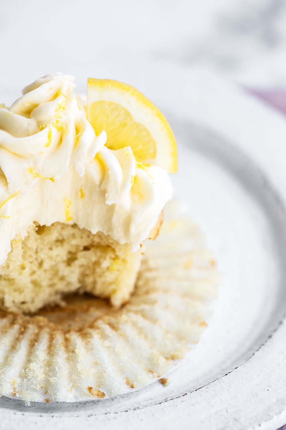 Lemon cupcake on plate with bite taken out