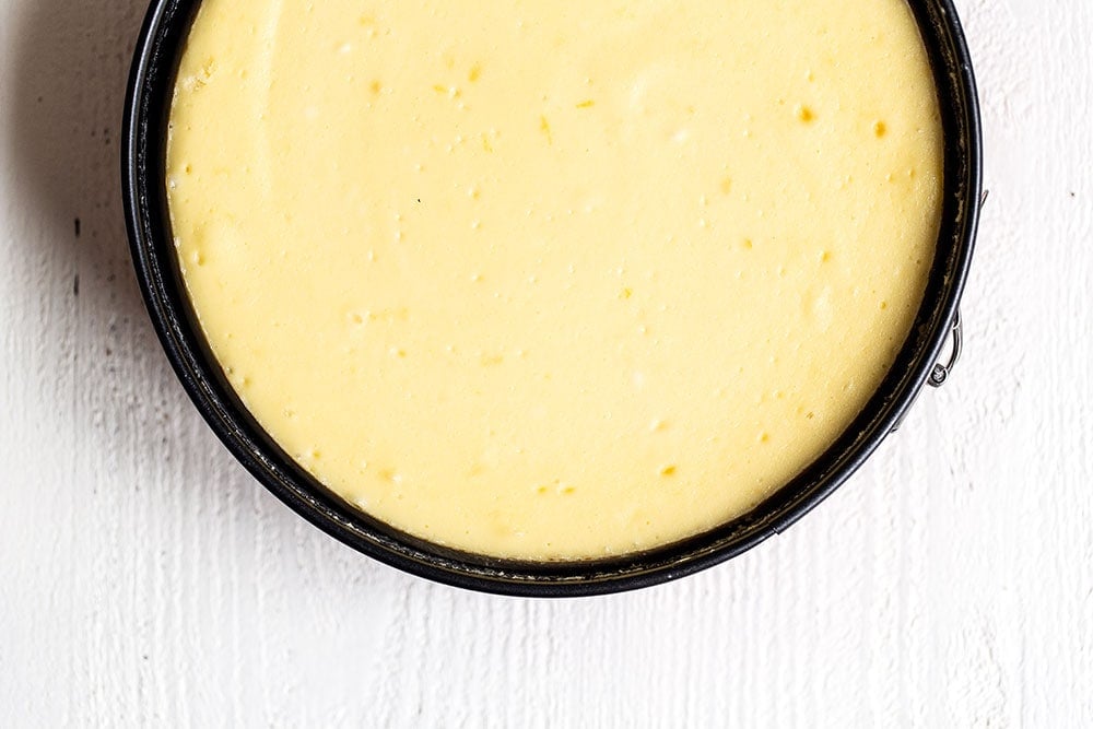 Baked cheesecake with smooth top before lemon curd