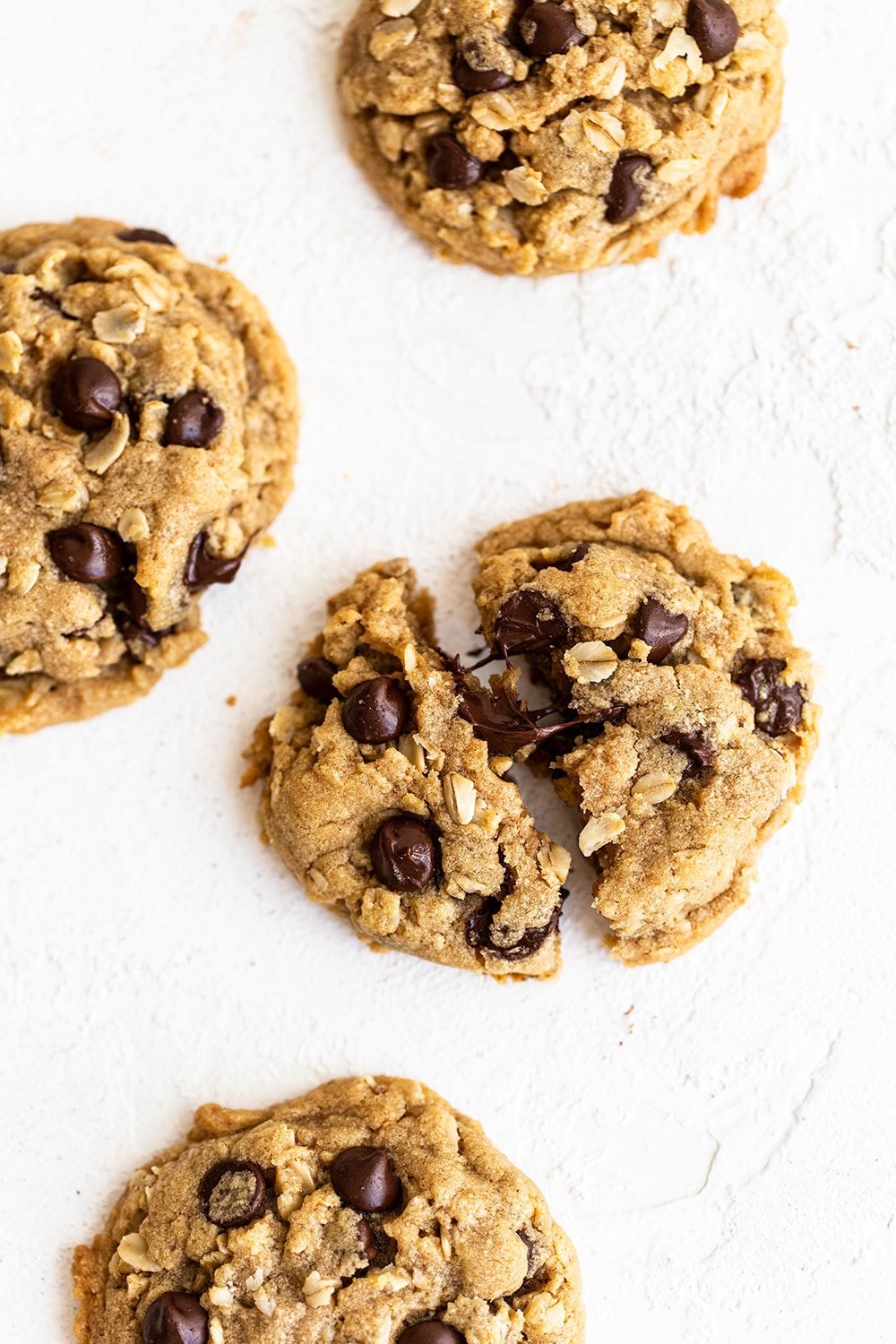 Peanut butter oatmeal chocolate chip cookies on the counter with one broken open with gooey chocolate chips